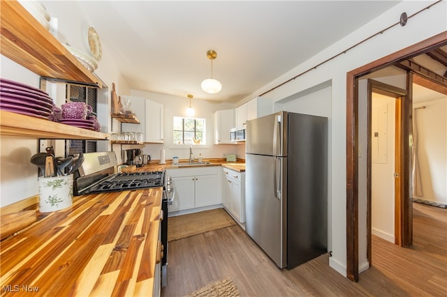 kitchen featuring white cabinetry, butcher block counters, stainless steel appliances, and pendant lighting