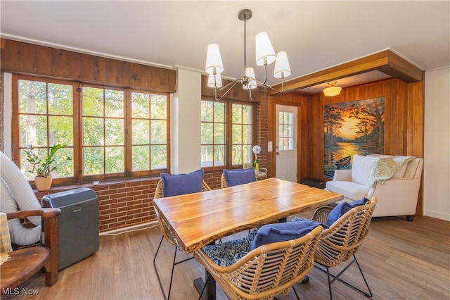 dining area featuring a notable chandelier, hardwood / wood-style floors, wooden walls, and plenty of natural light