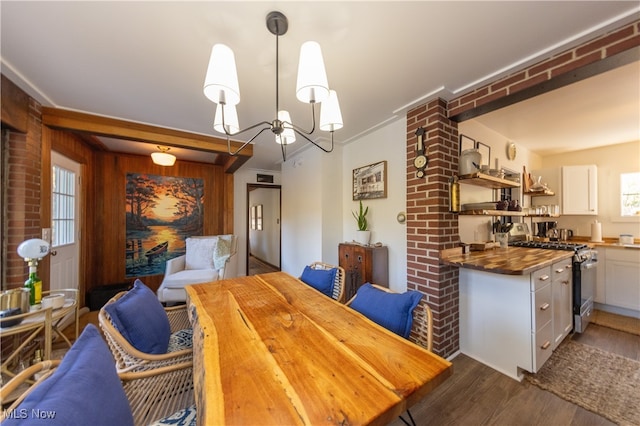 dining space featuring dark wood-type flooring, wooden walls, a healthy amount of sunlight, and a chandelier