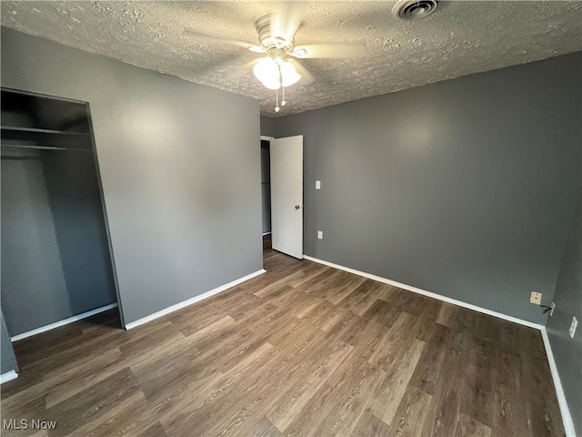 unfurnished bedroom featuring a closet, ceiling fan, a textured ceiling, and dark hardwood / wood-style flooring