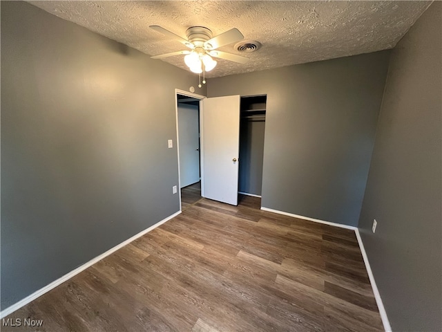 unfurnished bedroom featuring a closet, ceiling fan, hardwood / wood-style flooring, and a textured ceiling