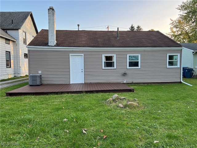 back house at dusk with cooling unit, a yard, and a deck