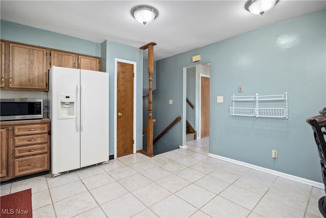 kitchen with white refrigerator with ice dispenser, backsplash, and light tile patterned floors