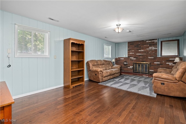 living room featuring a fireplace, dark wood-type flooring, and plenty of natural light