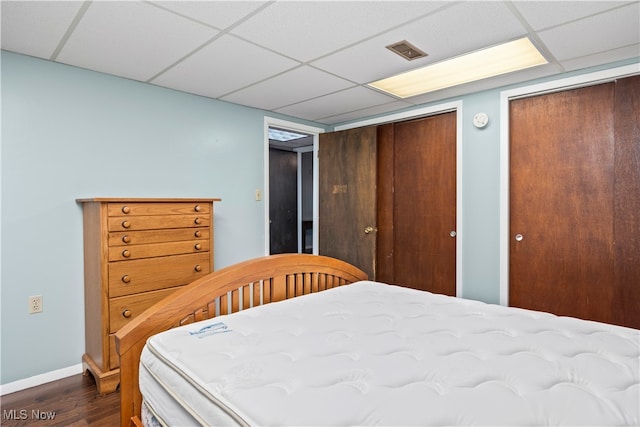 bedroom featuring dark wood-type flooring and a drop ceiling