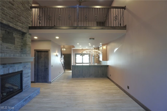 unfurnished living room featuring a high ceiling, light hardwood / wood-style flooring, and a large fireplace