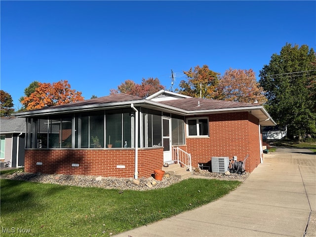 view of property exterior featuring a yard, a sunroom, and central AC