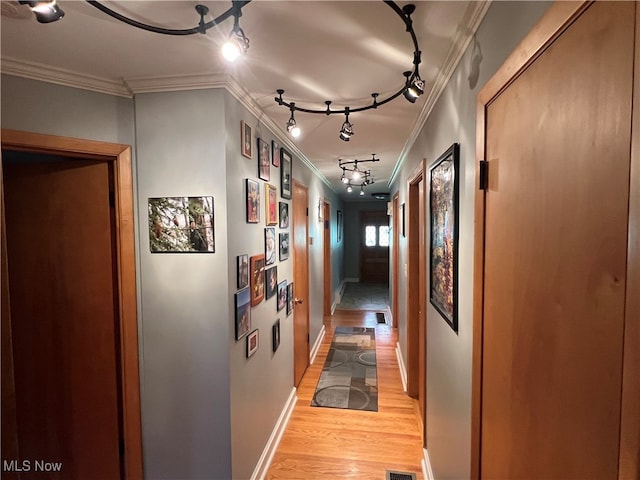 hall featuring light hardwood / wood-style floors, crown molding, and track lighting