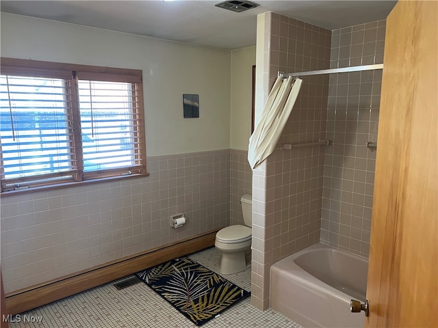 bathroom featuring tile walls, tile patterned floors, shower / bath combination with curtain, and toilet