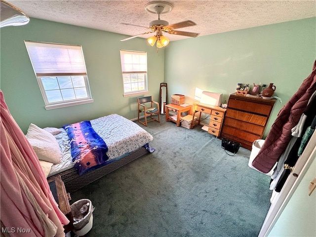 carpeted bedroom featuring ceiling fan and a textured ceiling