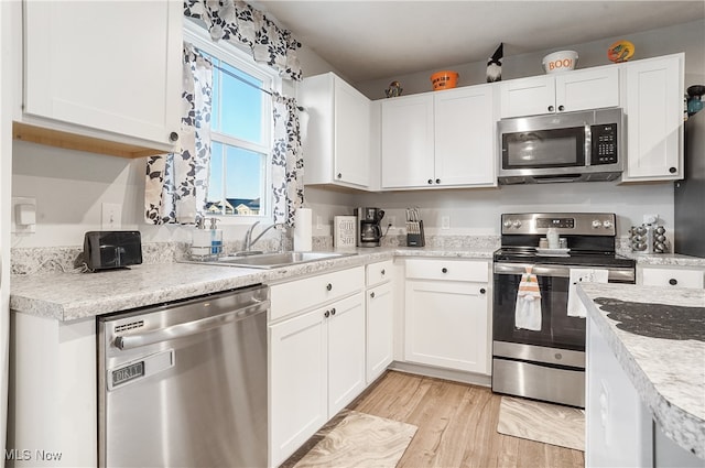 kitchen with light hardwood / wood-style floors, white cabinetry, stainless steel appliances, and sink