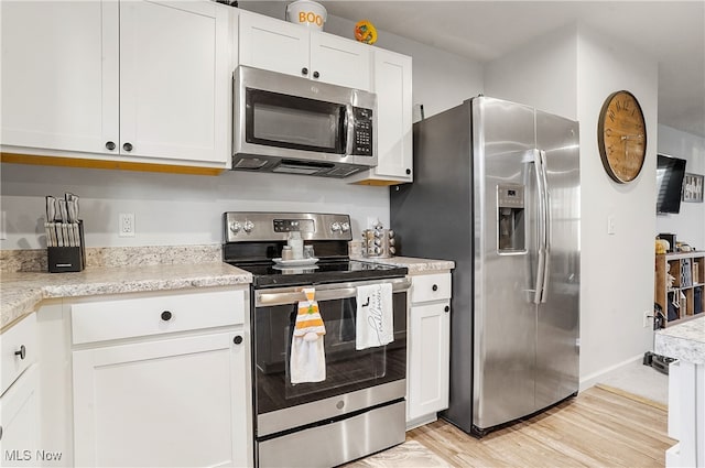 kitchen with white cabinets, stainless steel appliances, and light wood-type flooring