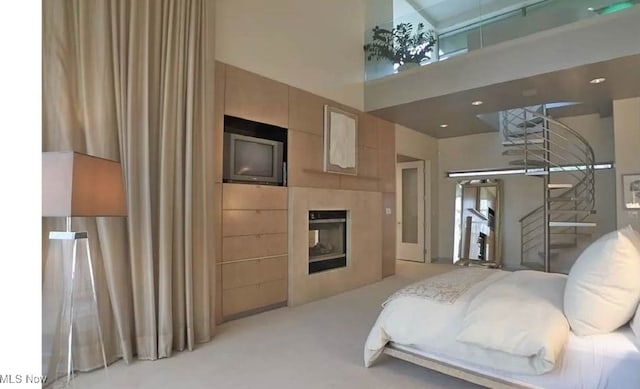 bedroom featuring a towering ceiling, a multi sided fireplace, and light colored carpet