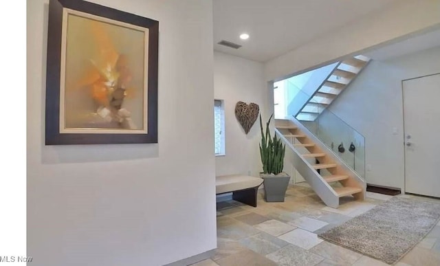 staircase featuring recessed lighting, stone finish floor, and visible vents