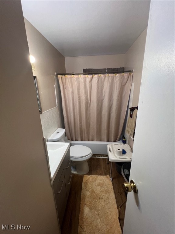 full bathroom with tasteful backsplash, hardwood / wood-style floors, toilet, shower / bath combo with shower curtain, and vanity