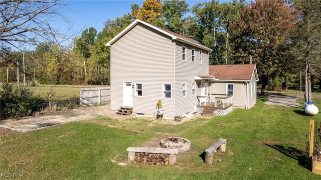 back of house with a fire pit, a yard, and a deck