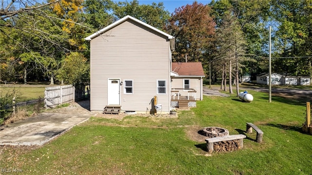 rear view of house featuring a wooden deck, an outdoor fire pit, and a lawn