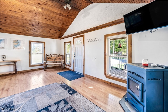 entryway featuring light hardwood / wood-style floors, a wood stove, wood ceiling, and ceiling fan