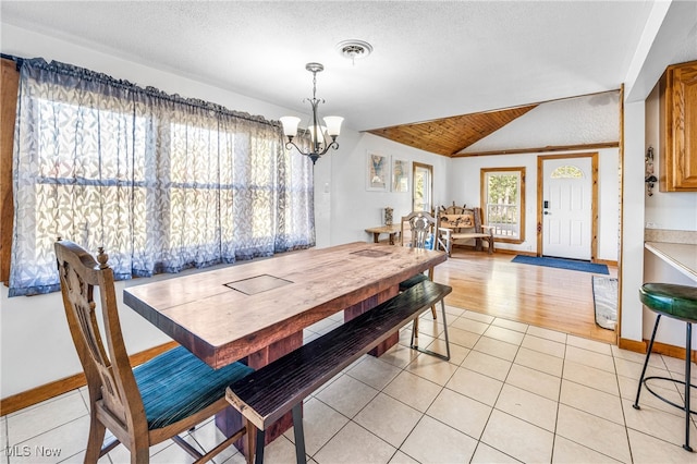 tiled dining room featuring a notable chandelier, a textured ceiling, and vaulted ceiling