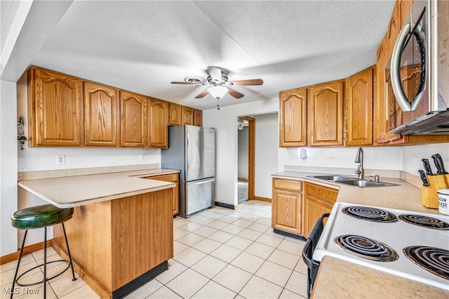 kitchen featuring a breakfast bar area, sink, appliances with stainless steel finishes, and a textured ceiling