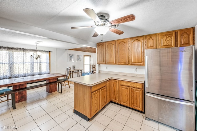 kitchen with pendant lighting, kitchen peninsula, plenty of natural light, and stainless steel fridge