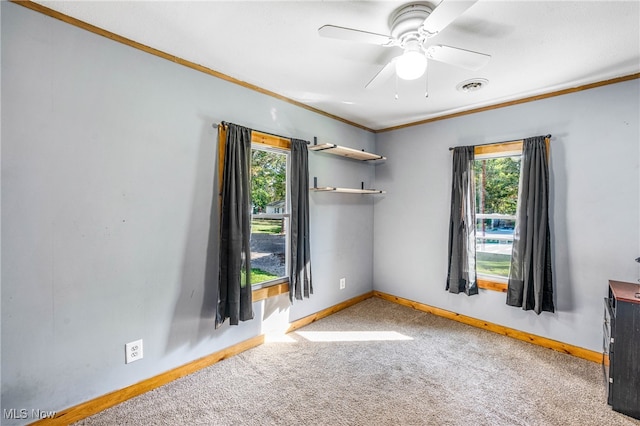 carpeted empty room featuring ceiling fan, a healthy amount of sunlight, and crown molding