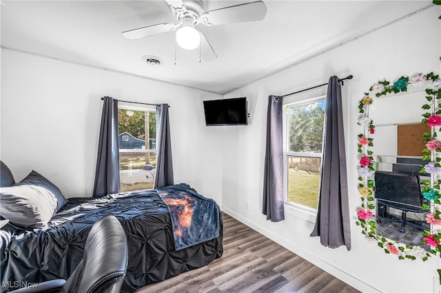 bedroom featuring hardwood / wood-style floors, multiple windows, and ceiling fan