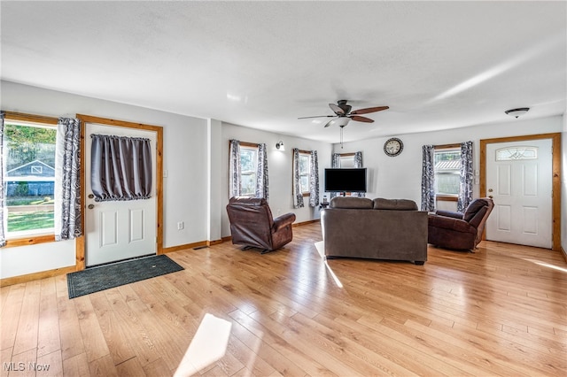 living room with light hardwood / wood-style flooring, a textured ceiling, and ceiling fan