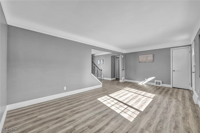 unfurnished living room with crown molding and light wood-type flooring