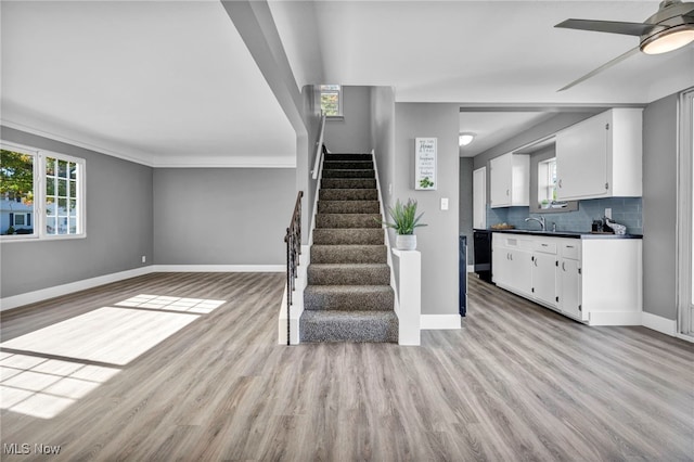 staircase featuring ceiling fan, crown molding, wood-type flooring, and sink