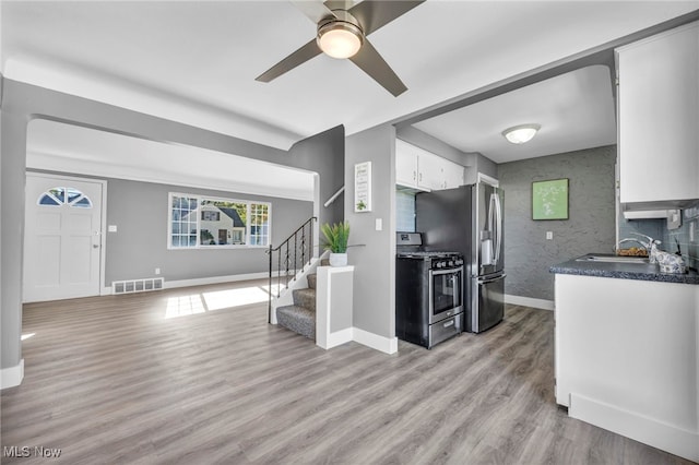 kitchen featuring sink, white cabinets, light wood-type flooring, appliances with stainless steel finishes, and ceiling fan