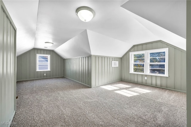 additional living space featuring wood walls, vaulted ceiling, and carpet floors