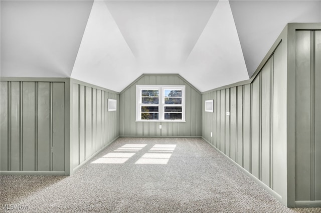 bonus room featuring vaulted ceiling, light colored carpet, and wood walls