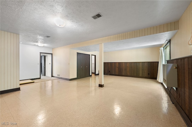 unfurnished room featuring wood walls and a textured ceiling