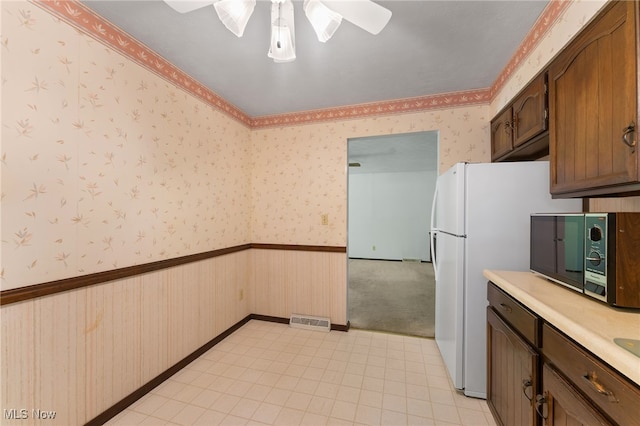 kitchen with ceiling fan, white refrigerator, and light colored carpet