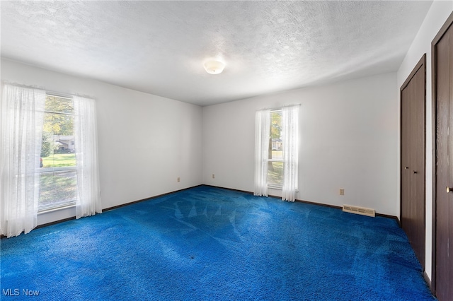 interior space with a textured ceiling and dark colored carpet