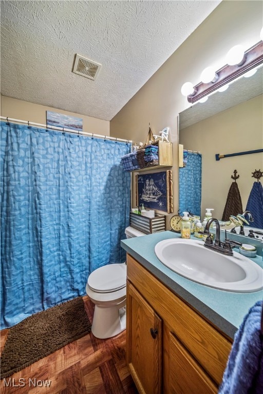 bathroom with vanity, parquet floors, a textured ceiling, and toilet