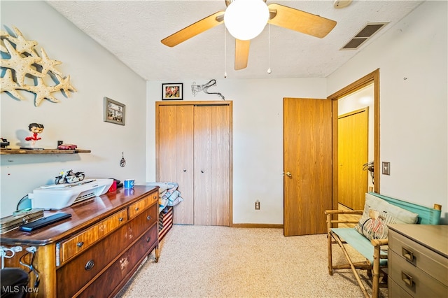 bedroom featuring ceiling fan, a closet, light carpet, and a textured ceiling