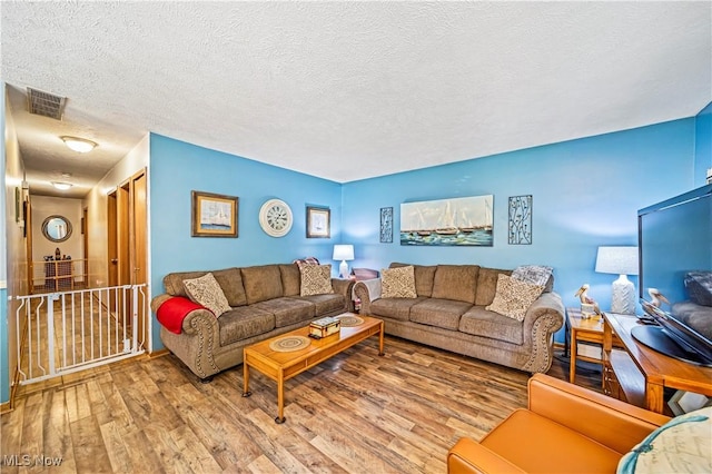 living room with wood-type flooring and a textured ceiling