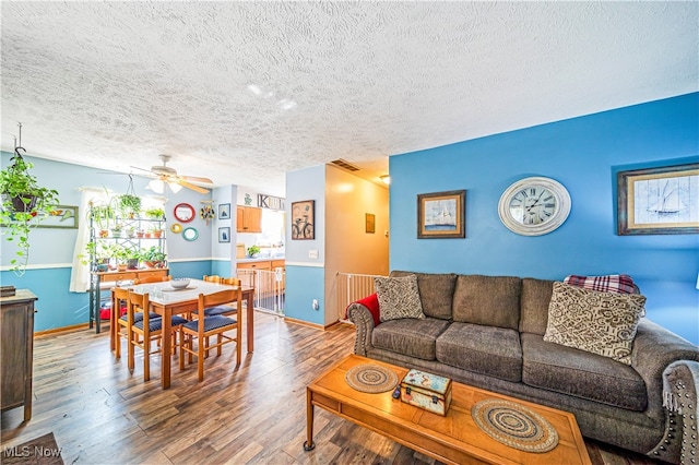 living room with ceiling fan, hardwood / wood-style floors, and a textured ceiling