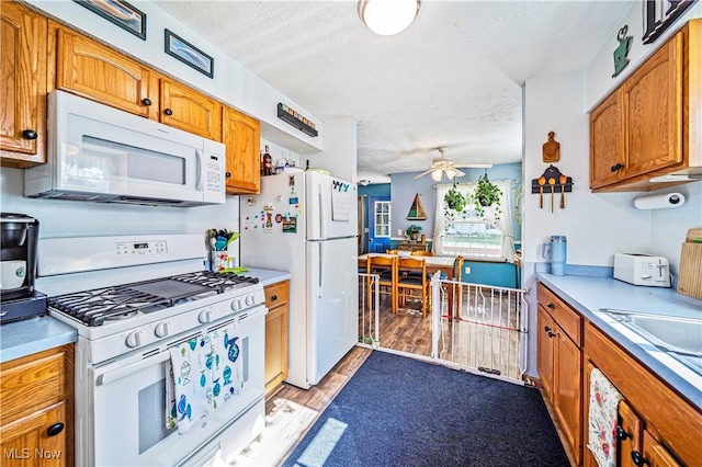 kitchen with ceiling fan, white appliances, a textured ceiling, and light wood-type flooring