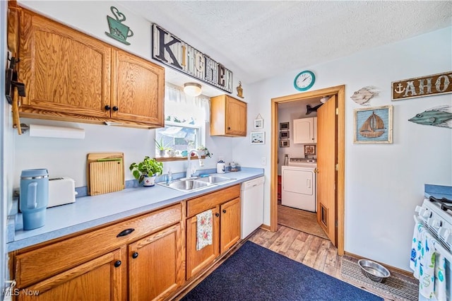 kitchen featuring sink, a textured ceiling, white appliances, washer / clothes dryer, and light hardwood / wood-style floors