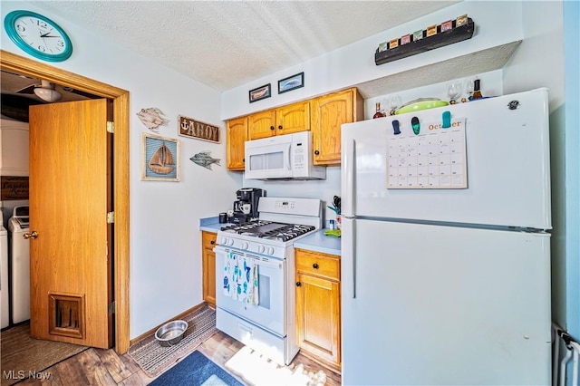 kitchen featuring white appliances, washing machine and clothes dryer, a textured ceiling, and light wood-type flooring