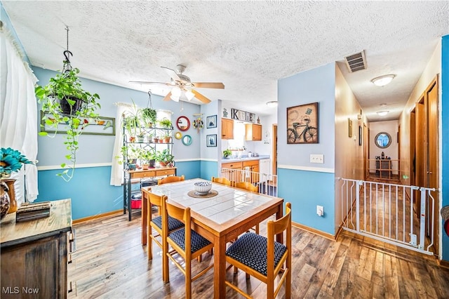 dining room with ceiling fan, wood-type flooring, and a textured ceiling