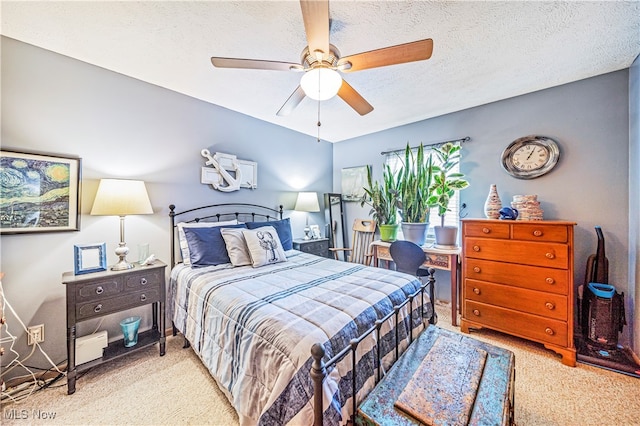 bedroom with ceiling fan, light colored carpet, and a textured ceiling