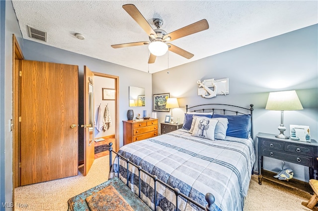 bedroom with ceiling fan, light colored carpet, and a textured ceiling