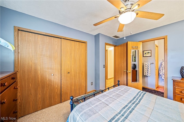 bedroom featuring ceiling fan, a closet, a textured ceiling, and carpet flooring