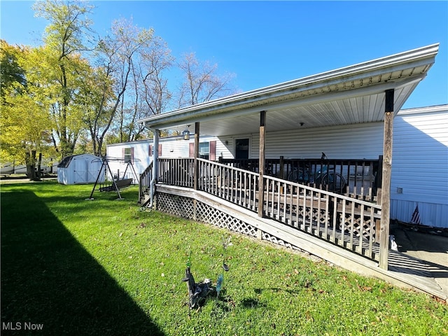 rear view of house featuring a yard, a deck, and a storage unit