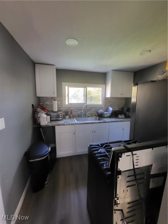 kitchen featuring stainless steel fridge, tasteful backsplash, dark hardwood / wood-style flooring, white cabinetry, and sink