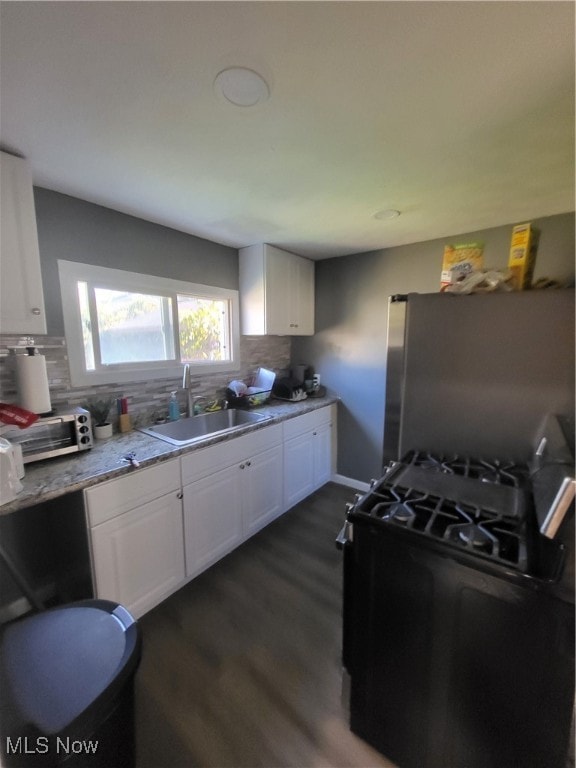 kitchen featuring sink, stainless steel fridge, white cabinets, dark wood-type flooring, and decorative backsplash